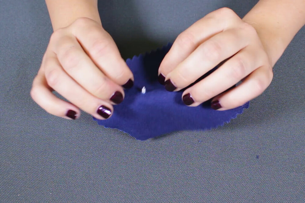 How To Attach a Jeans Button - Pierce the button through the wrong side of the fabric